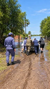 Personal policial y otros agentes avanzan por una calle anegada.