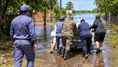 Personal policial y otros agentes avanzan por una calle anegada.