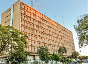 Fachada de un edificio institucional con árboles en primer plano.