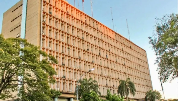 Fachada de un edificio institucional con árboles en primer plano.