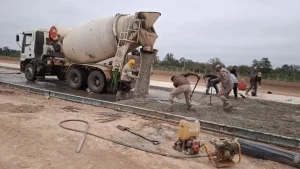 Camión hormigonera y trabajadores colocan concreto en la pista de Misión Nueva Pompeya