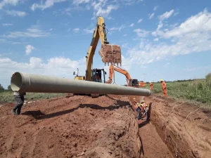 Trabajadores instalan una cañería de gran diámetro con maquinaria pesada