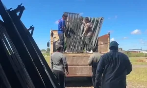 Operarios cargan paneles metálicos en un camión en un área abierta