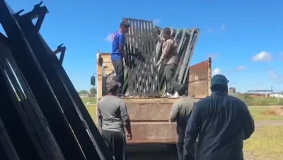Operarios cargan paneles metálicos en un camión en un área abierta