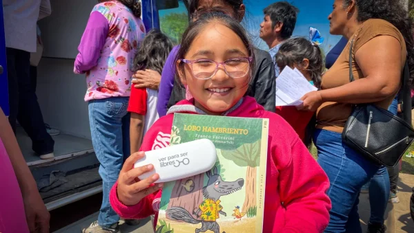 Una estudiante con anteojos sostiene los lentes del programa Ver para Ser Libres junto a un cuaderno escolar durante un operativo en Chaco.